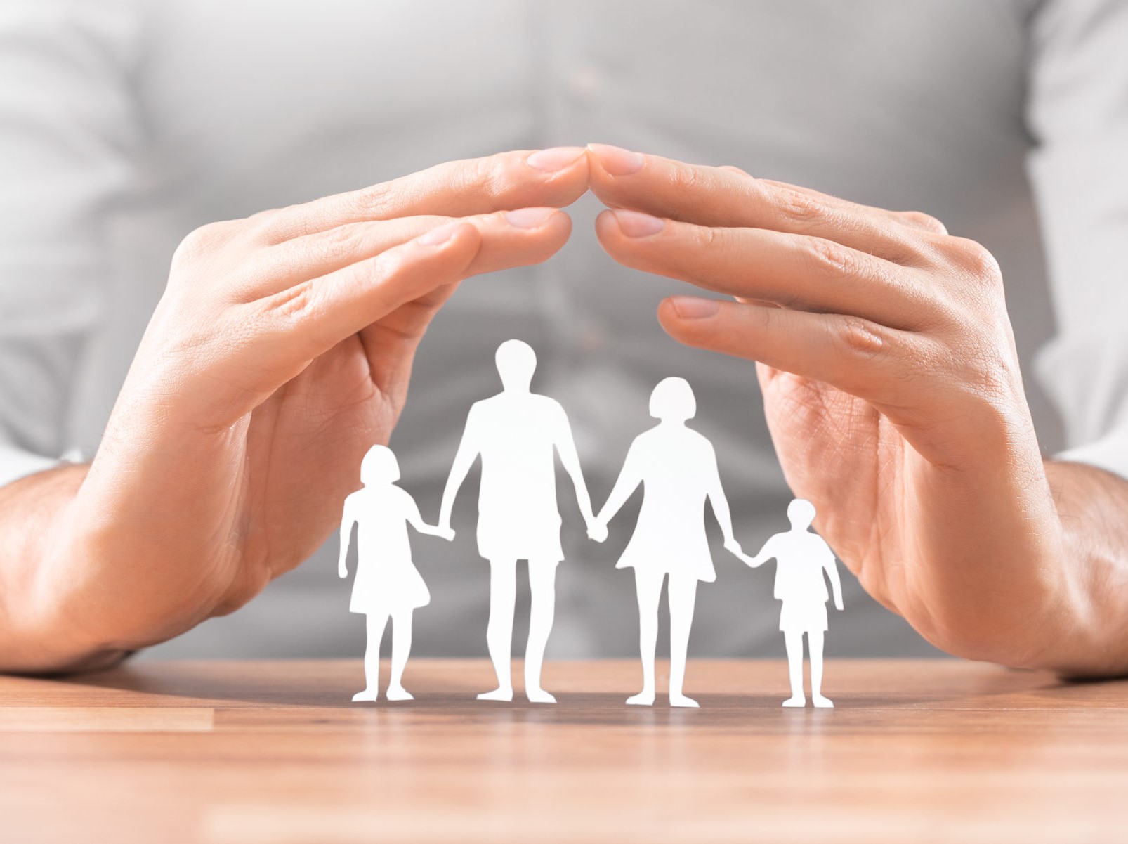 Hands with cut out paper silhouette on table. Family care concept.