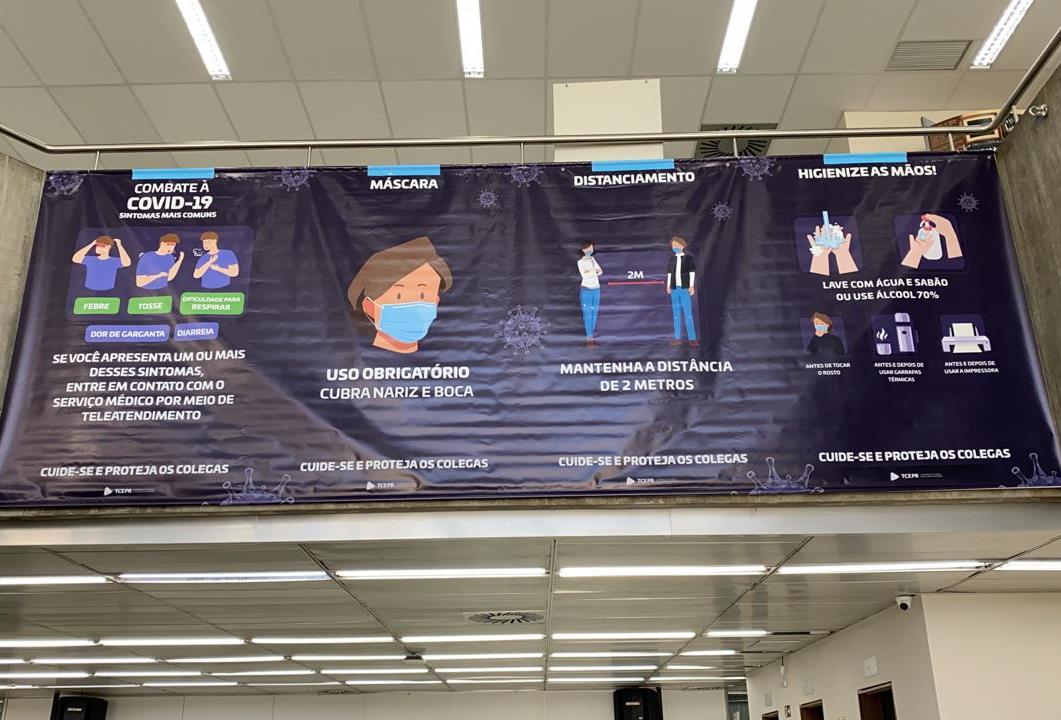 Cartaz na recepção do TCE-PR informa as medidas de segurança obrigatórias contra a disseminação da Covid-19 que devem ser cumpridas por quem ingressa no prédio. Foto: Divulgação/TCE-PR