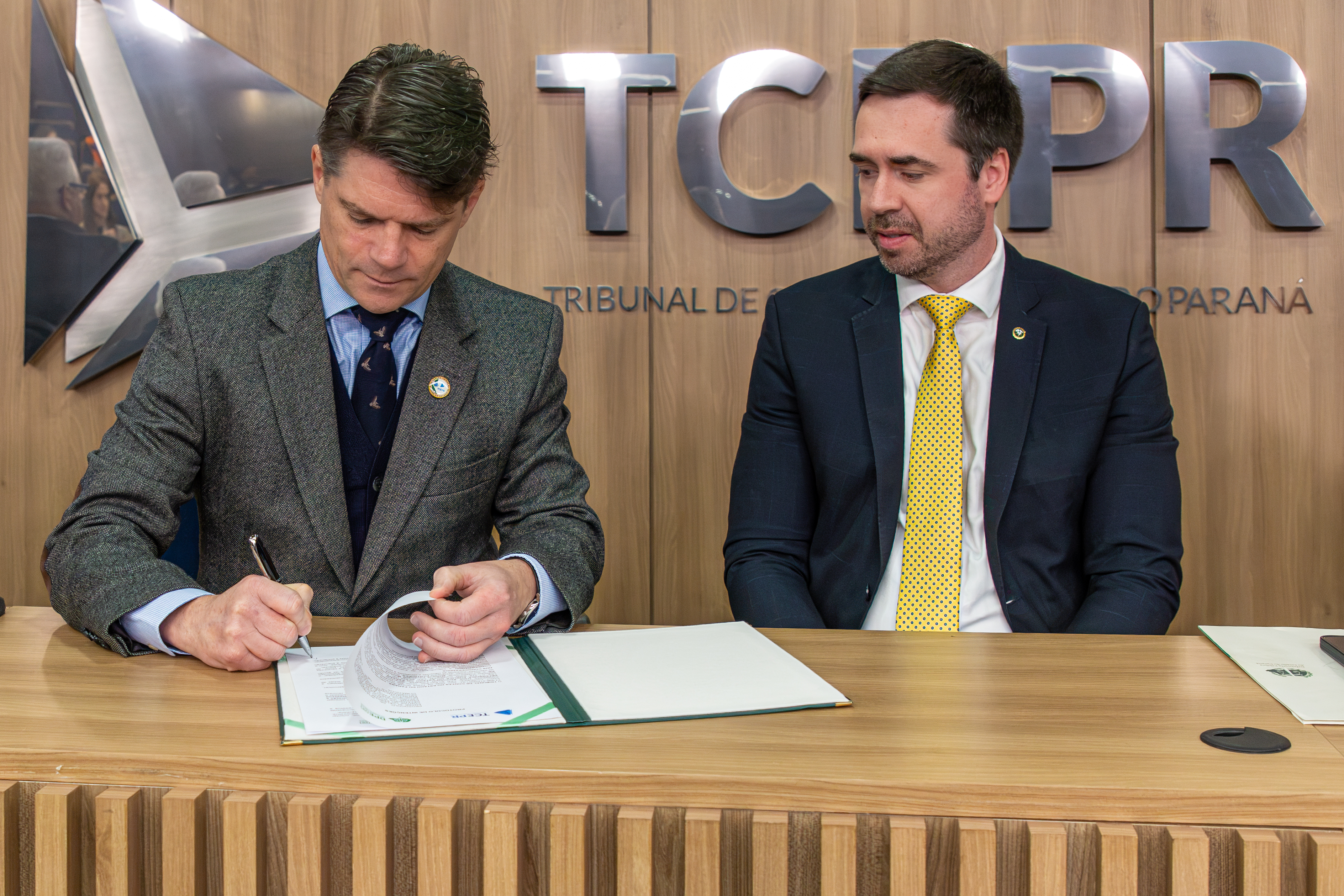 O presidente do TCE-PR, conselheiro Ivens Linhares, e o defensor público geral do Estado, Matheus Munhoz, assinam protocolo de intenções