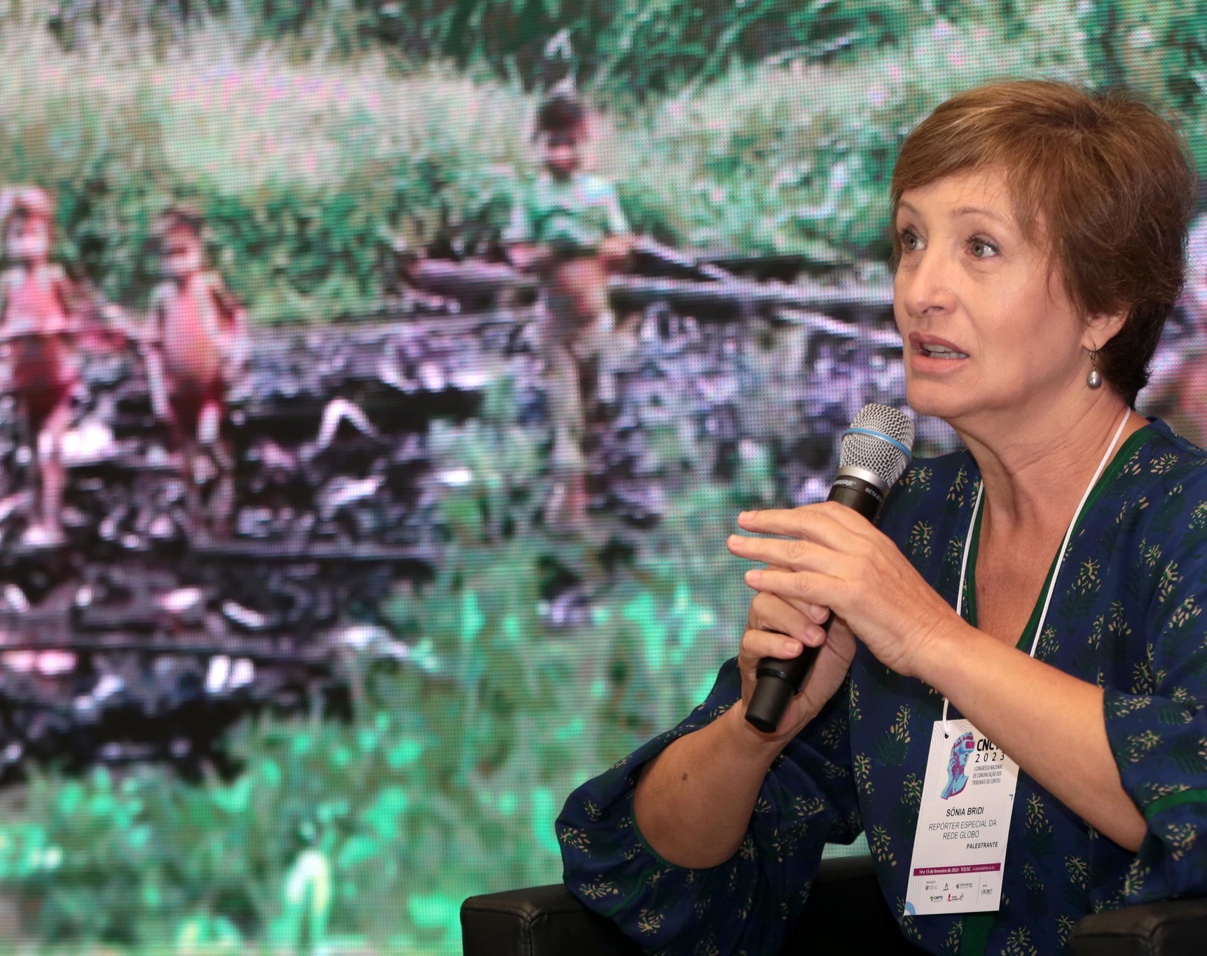 A jornalista Sônia Bridi durante palestra na abertura do 1º Congresso Nacional de Comunicação dos Tribunais de Contas (CNCTC 2023); ao fundo, imagens de crianças yanomamis vítimas de desnutrição e doenças. Foto: Atricon/Divulgação