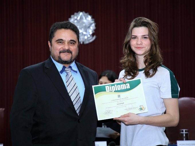 O supervisor de Capacitação do TCE-PR, Anderson Saladino, entrega o diploma a Natália Wolff, eleita vereadora mirim pelos colegas do Colégio Sesi Boqueirão, de Curitiba. Foto: Wagner Araújo/Divulgação TCE-PR