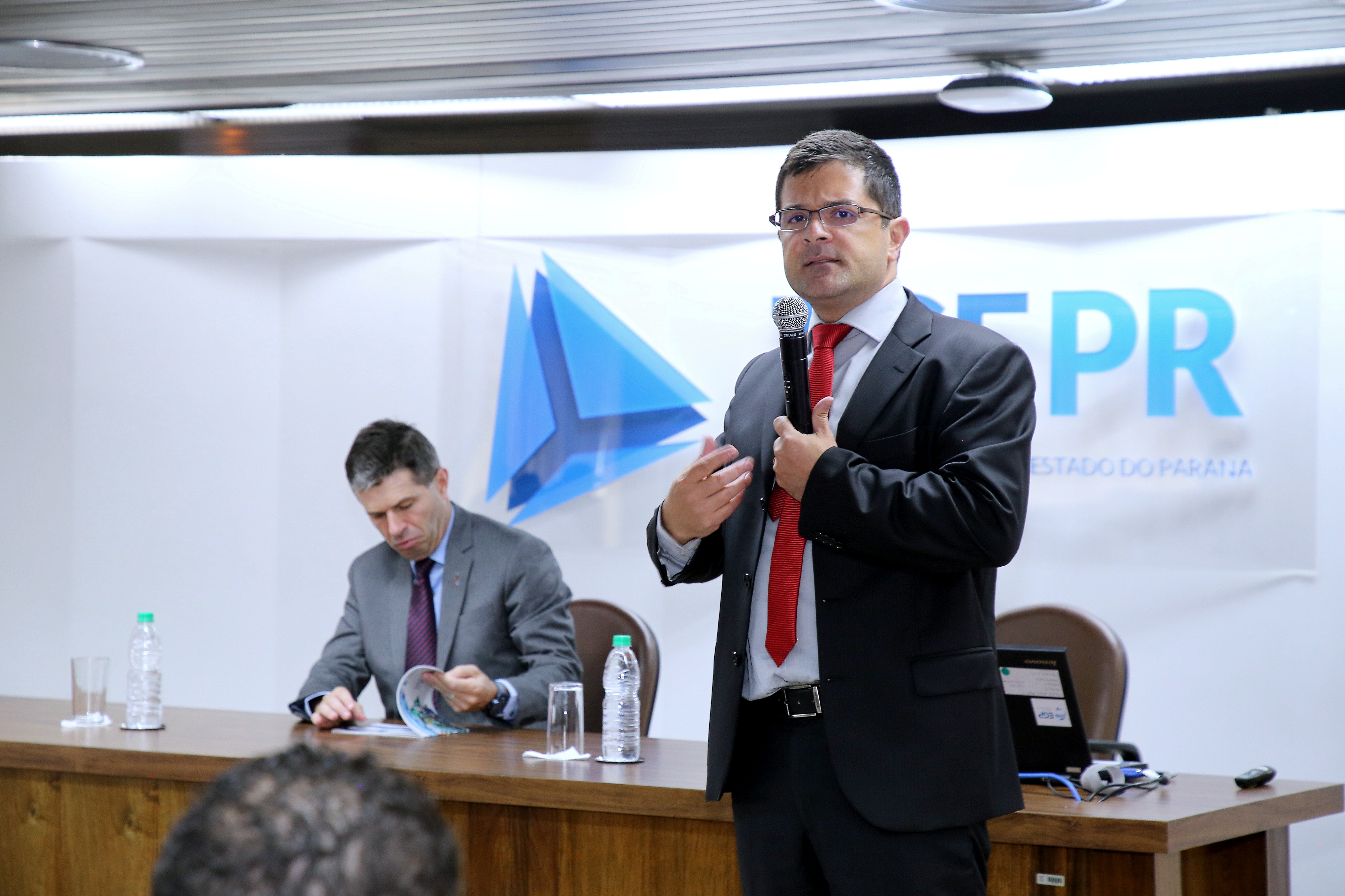 O coordenador-geral de Fiscalização do TCE-PR, Rafael Ayres, realiza a abertura de curso sobre transferências voluntárias no auditório do Tribunal, acompanhado pelo procurador-geral do MPC-PR, Flávio Berti