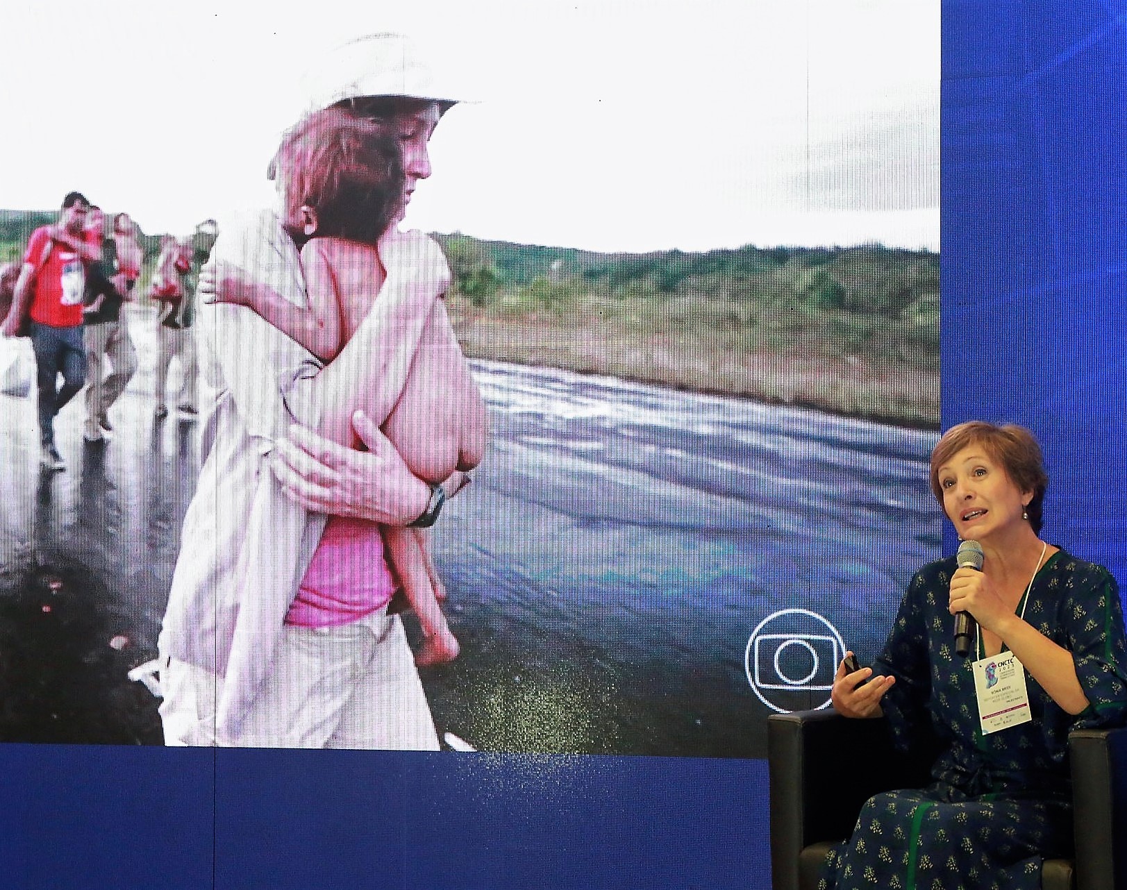 A jornalista Sônia Bridi durante palestra na abertura do 1º Congresso Nacional de Comunicação dos Tribunais de Contas (CNCTC 2023); ao fundo, imagem dele socorrendo bebê yanomami vítima de desnutrição e doenças. Foto: Atricon/Divulgação