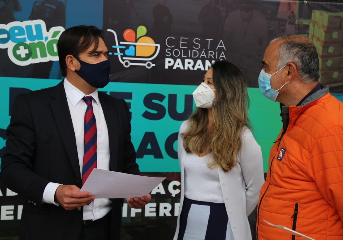 O diretor-geral, Evandro Arruda, entrega à primeira-dama, Luciana Saito Massa, e ao coronel Fernando Raimundo Schunig, coordenador Estadual da Defesa Civil, os alimentos arrecadados no TCE-PR para a Campanha Cesta Solidária Paraná. Foto: Dilton Leandro Vaz/Divulgação TCE-PR