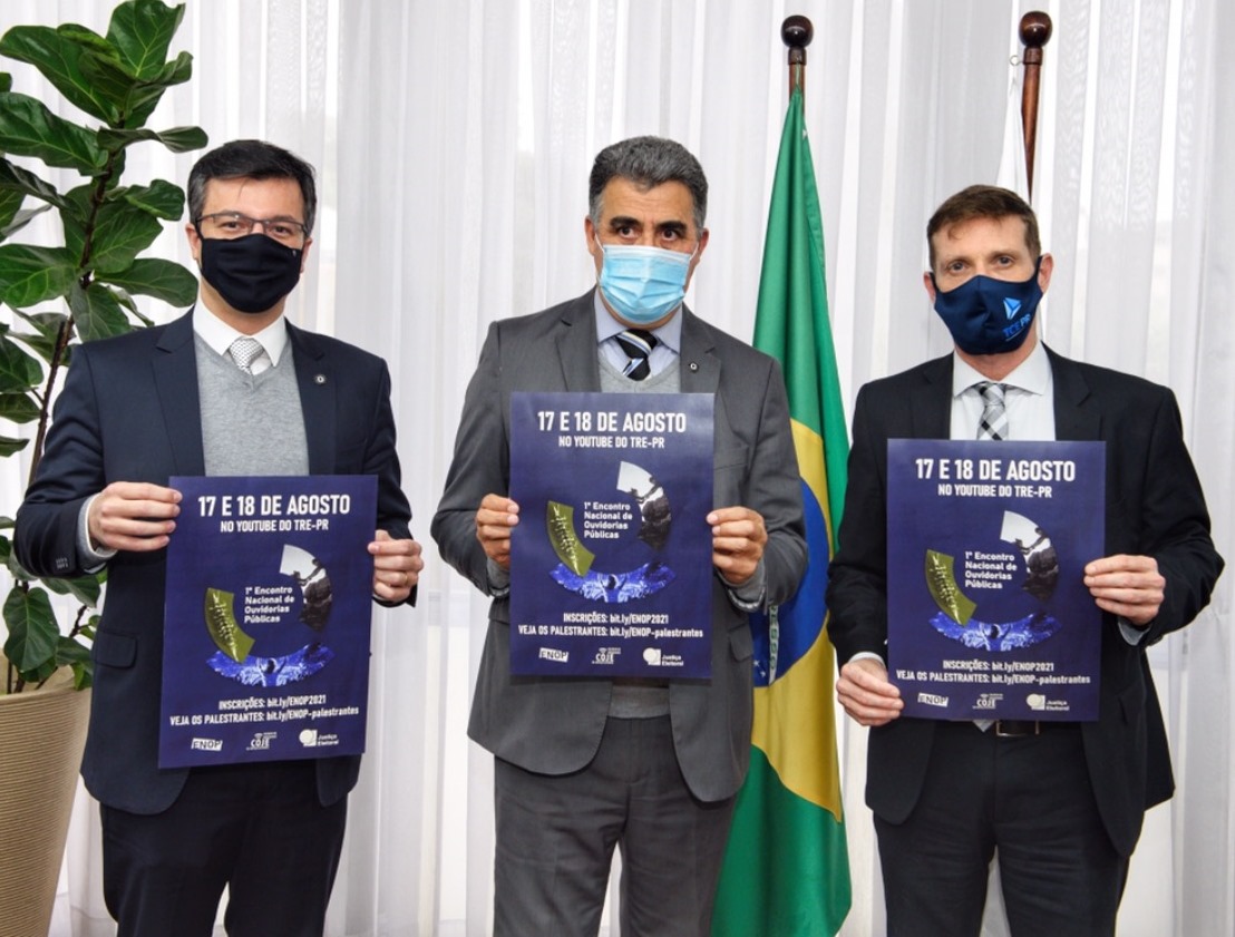 O juiz eleitoral Thiago Paiva dos Santos, ouvidor do TRE-PR; o presidente daquele órgão, desembargador Tito Campos de Paula; e o presidente do TCE-PR, conselheiro Fabio Camargo, seguram o cartaz do 1º Encontro Nacional de Ouvidorias Públicas (Enop). Foto: Denis Ferreira Neto/Divulgação TCE-PR